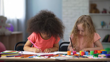 Two Multi-racial Girls Drawing With Colorful Pencils In Early Education Center