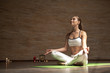 Calm relaxed beautiful lady sitting on the yoga mat with her eyes closed and meditating in lotus pose