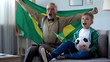 Grandpa waving Brazil flag, together with boy celebrate victory of football team