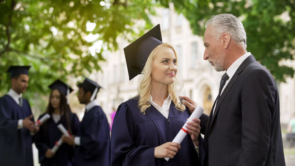 Wall Mural - Happy blonde graduate student rejoicing diploma with father, graduation ceremony