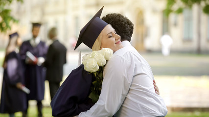 Wall Mural - Boyfriend giving flowers to his graduate girlfriend and hugging special occasion