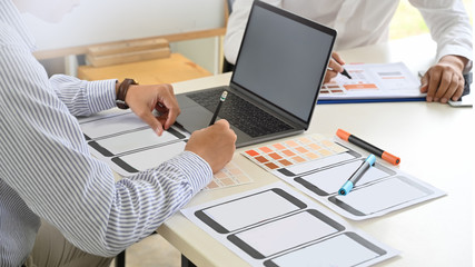 UI UX designer sketching layout design  application on mockup mobile phone in studio.