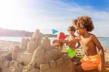 Happy Kids Decorating Sandcastle Towers With Flags
