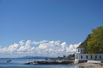 Wall Mural - Castine, Maine, USA: Beautiful white clouds in a blue sky over the harbor at Castine, with small boats in Penobscot Bay and mountains in the distance.