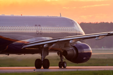 Modern twin engine civil airplane taxiing for take off at International airport during sunrise.