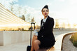 © mnelen.com - confident beautiful woman stewardess in uniform sitting and waiting for flight with suitcase