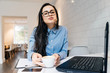 © mnelen.com - funny young brunette girl in blue shirt sitting in cafe and eating a sandwich with coffee, close laptop for work