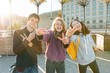 © Valerii Honcharuk - Portrait of friends teen boy and two girls smiling, making funny faces, showing victory sign in the street. City background, golden hour