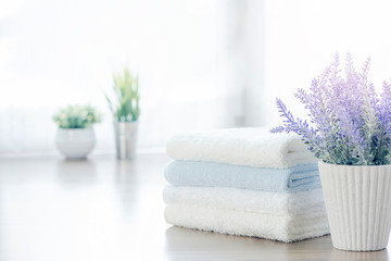 Mockup stack of white towels and houseplant on white table with copy space.