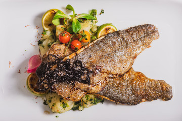 Grilled trout, two slices with vegetables served on a plate