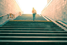 Woman Climbs The Stairs To A Bright Light At The End Of The Tunnel.