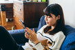 © Wataru Kitamura - ソファーでくつろぎながらタブレットを使用する女性