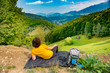 © Creatikon Studio - Young mountain hiker sitting on a waterproof nylon blanket in a beautiful mountain landscape and enjoying the view. Hiker concept for summer designs.