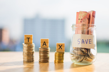 coin of money on wooden table and text TAX SAVE with blur background.