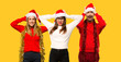 © luismolinero - A group of people Blonde woman dressed up for christmas holidays takes hands on head because has migraine on yellow background