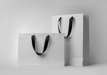 Wall Mural - Paper shopping bags with ribbon handles on white background. Mockup for design