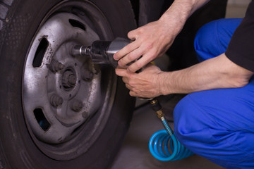 Mechanic is pumping up wheels in service station