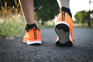 Closeup people walking with orange shoes on road in park for health concept.