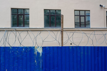 The building behind the blue fence with barbed wire