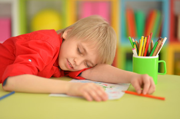 Portrait of cute little boy sleeping on table