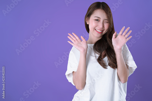 Fotografie, Obraz Asian woman glad and hand up, white t-shirt clothing, purple background