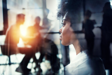 Businesswoman at the office looks through the window for the future. double exposure