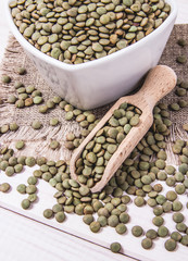 Wall Mural - Green lentils in a bowl on a wooden background.