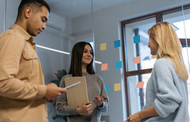 Wall Mural - Group of happy multiracial business people working project, planning strategy, talking, discussion creative idea in modern office. Smiling colleagues meeting, collaborate, using sticky notes and scrum