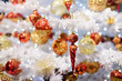 Branch of white artificial Christmas tree decorated with gold and red balls. Close up.