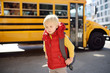 Pupil with schoolbag with yellow school bus on background