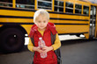 Pupil with schoolbag and bottle of water with yellow schoolbus on background.