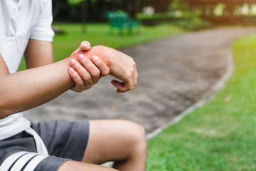 Young man asian have accident and holding him wrist pain twist sprain in sport exercise jogging, selective focus.