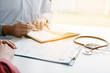 © wutzkoh - The doctor is writing the appointment letter to the patient at the clinic.