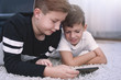 © sakkmesterke - Little boys using smartphone on carpet