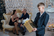 © Vladimir - Son holding a Christmas gift in his hands on the background of happy parents