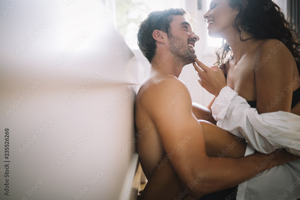 Young couple being intimate in bedroom. Sensual lovers making love in bedroom. - obrazy, fototapety, plakaty 