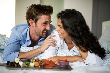 Romantic happy couple having breakfast in bed