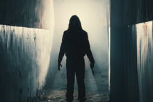 Silhouette Of Man Maniac Or Killer Or Horror Murderer With Knife In Hand In Dark Creepy And Spooky Corridor. Criminal Robber Or Rapist Concept In Thriller Atmosphere