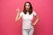 Image of surprised young woman standing isolated over pink background
