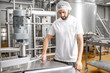© rh2010 - Portrait of a handsome worker in uniform near the stainless tank full with fermenting milk at the cheese manufacturing