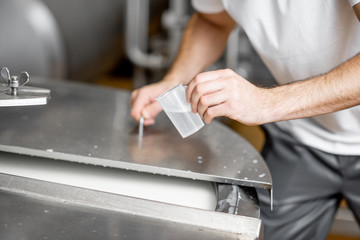 Wall Mural - Worker adding supplements during the milk fermentation process in the stainless tank at the cheese manufacturing. Close-up view with no face