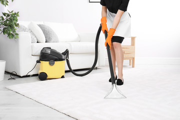 Wall Mural - Woman cleaning carpet with vacuum cleaner, closeup