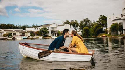 Wall Mural - Romantic couple sitting in a boat and kissing