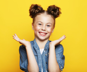 Wall Mural - Portrait of cheerful smiling little girl on yellow background 