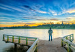 © huythoai - Da Lat, Vietnam - October 29th, 2018: Man standing on a small bridge reflecting on the lake at sunrise as a relaxing way to welcome the beautiful new day