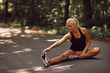 Fit young woman stretching on a forest road before jogging