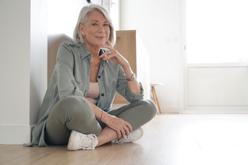 Wall Mural -  Attractive senior woman sitting on the floor at home