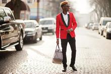 Fashion African American Man Model At Red Suit, With Highlights Hair And Handbag Posed At Street.