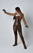 © faestock - full length portrait of brunette  girl wearing brown leather steampunk outfit. standing pose, holding a gun. on grey studio background.