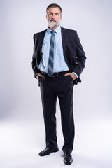 Full length portrait of confident mature businessman in formals standing isolated over white background.